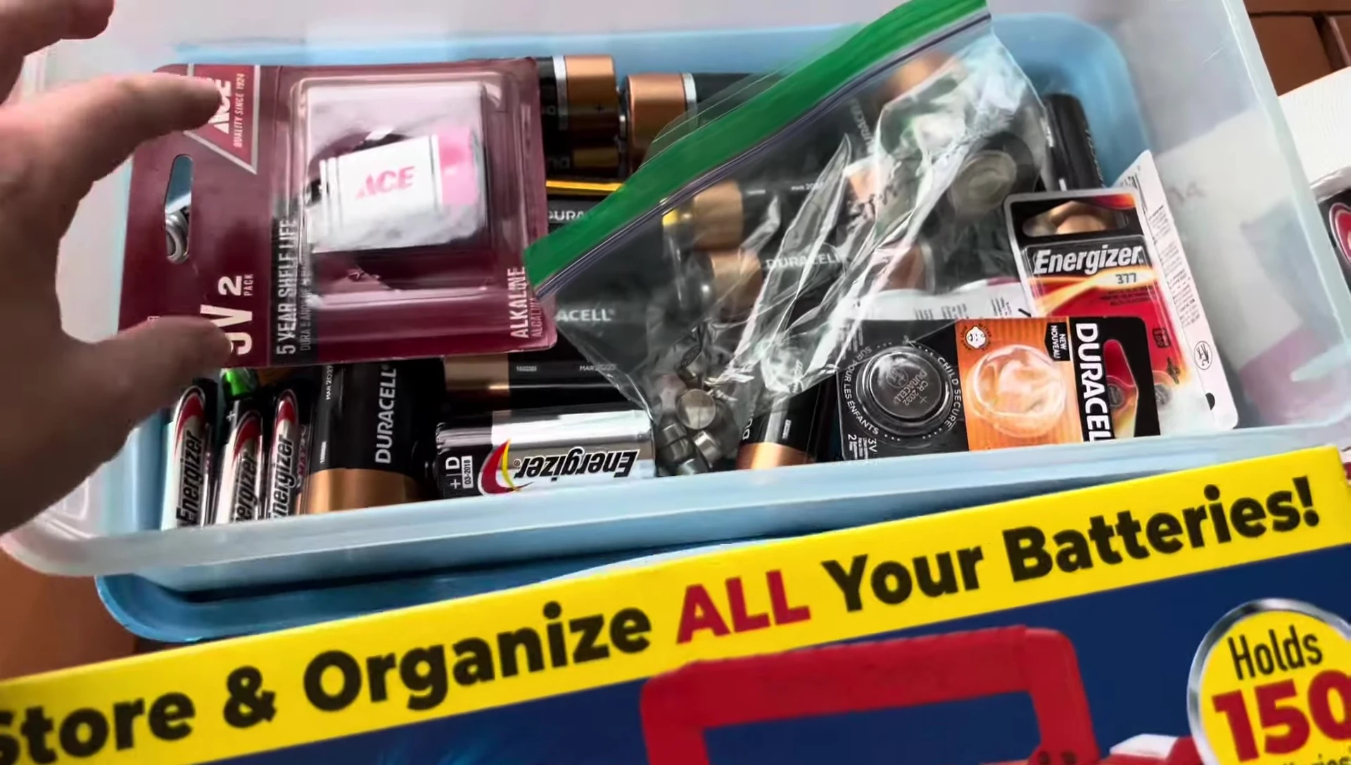 Close-up view of the disorganized batteries and packaging within the shoebox.