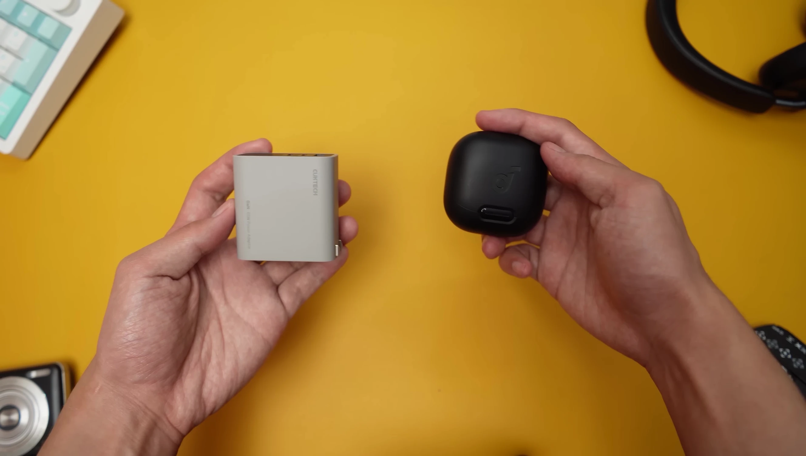 The charger next to wireless earbuds to illustrate its small size.