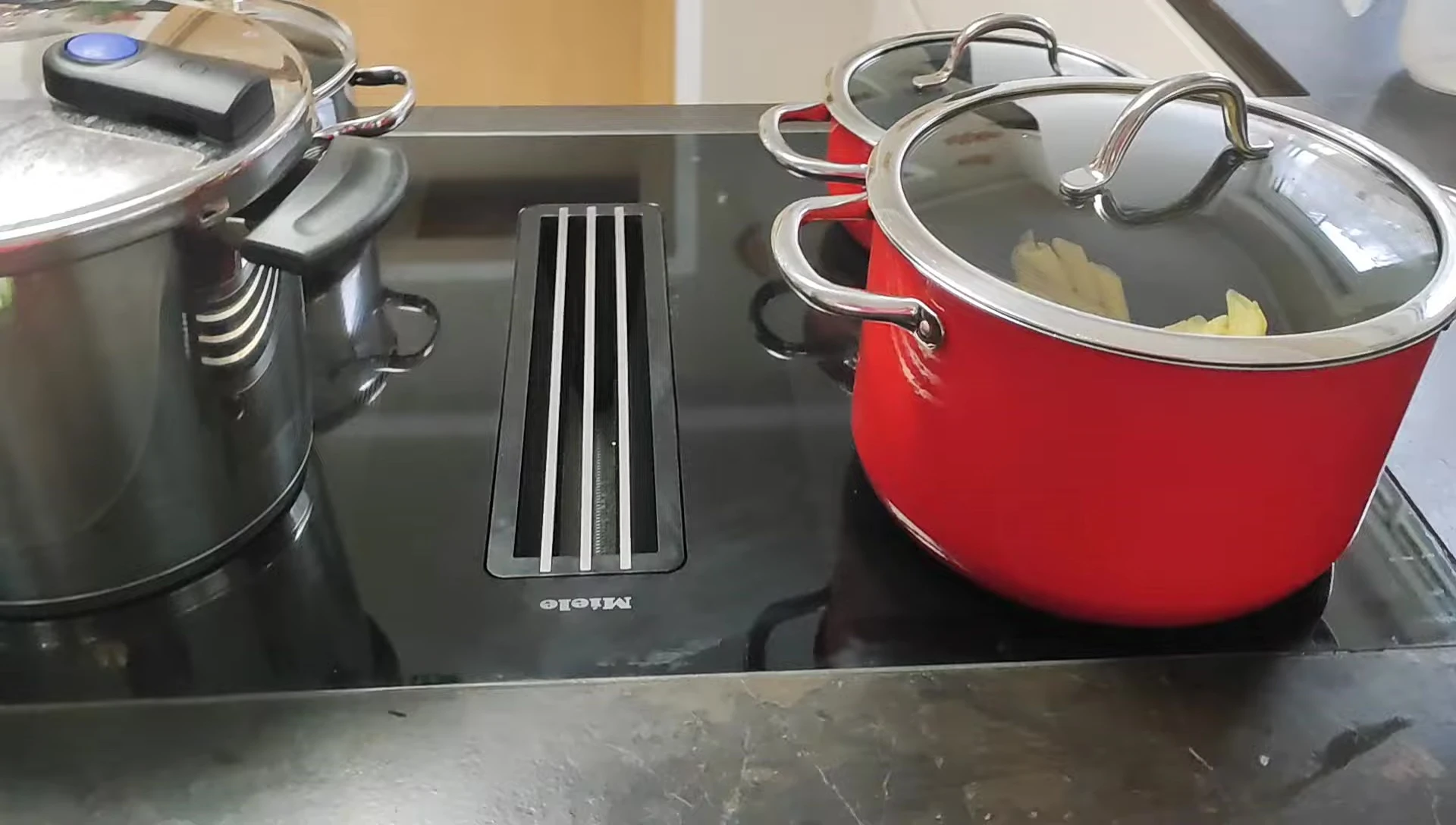 Four pots of different sizes cooking simultaneously on the cooktop