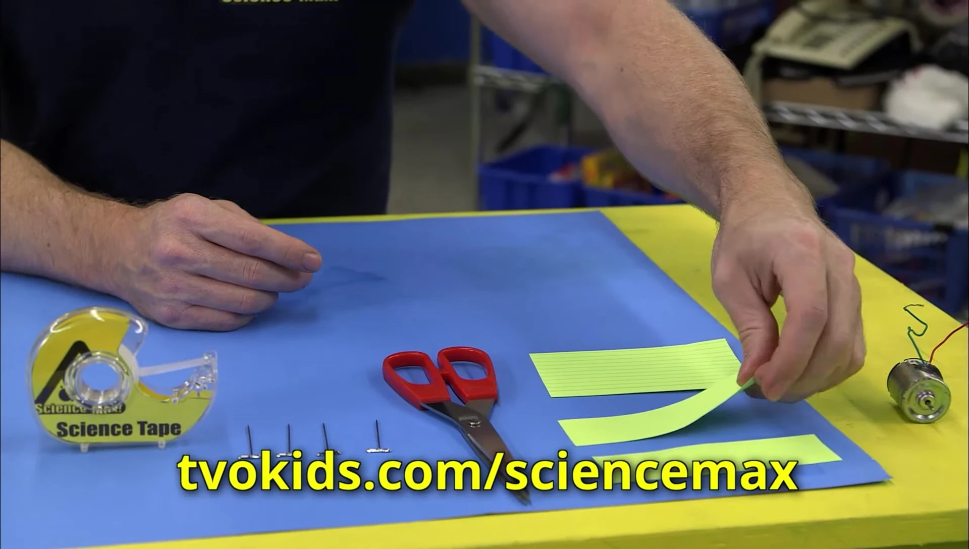 Close-up showing the process of attaching pushpins to index card strips.