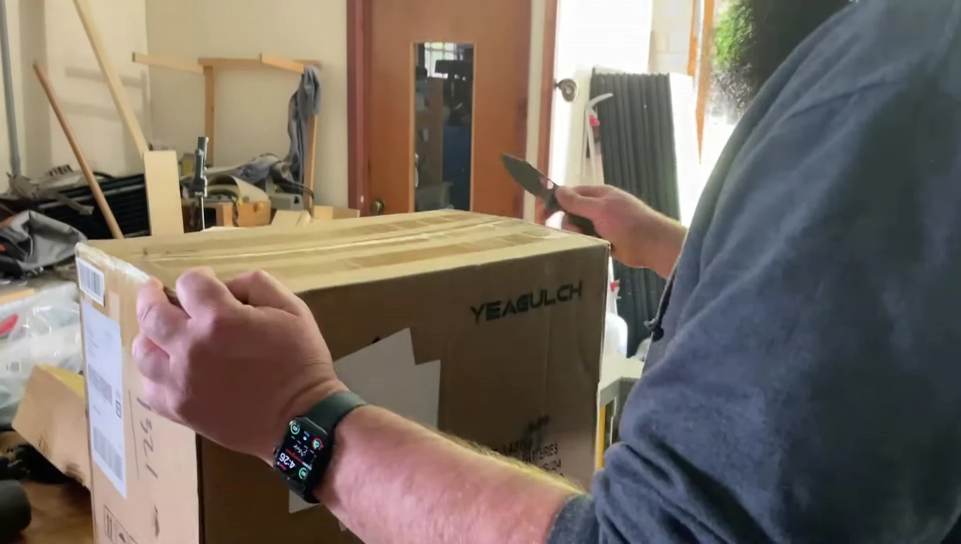 The speaker using a pocket knife to open the packaging