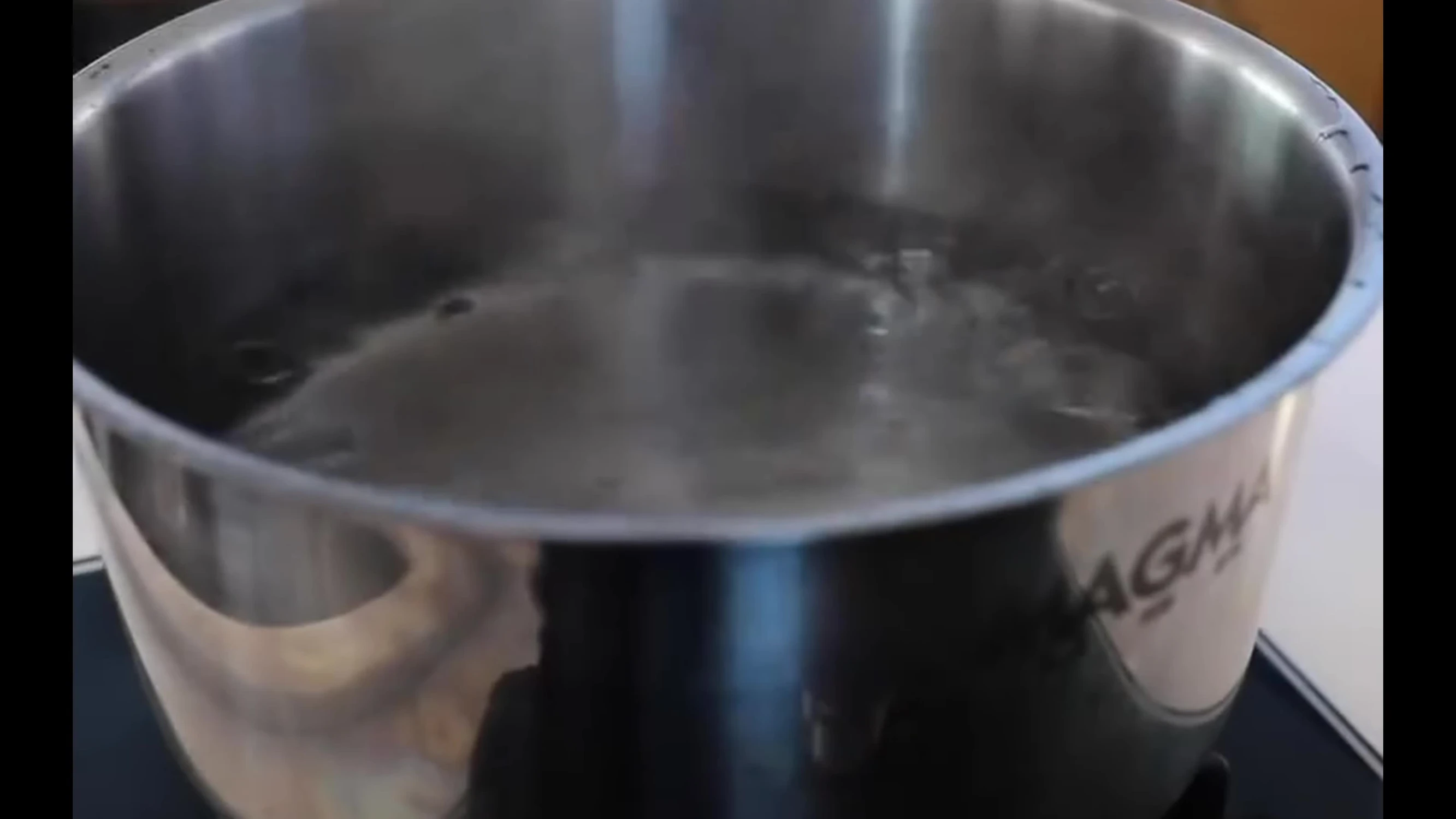 A person using a kettle to heat water for a shower on a boat