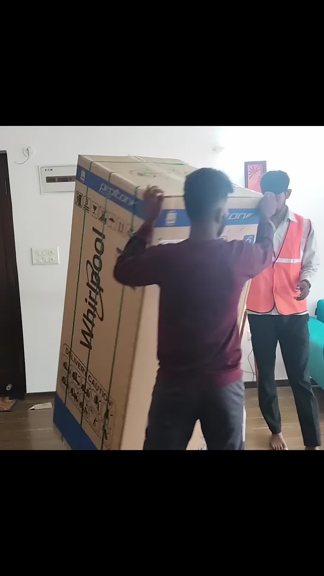 The large refrigerator box nearly touching the ceiling during unboxing.